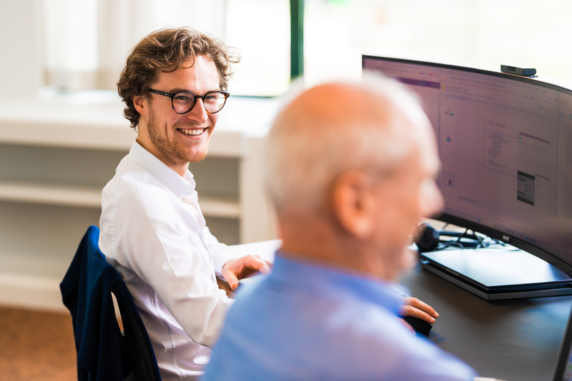 OBS-consultant zit naast een klant in een kantooromgeving, beiden kijken naar een scherm met Odoo.